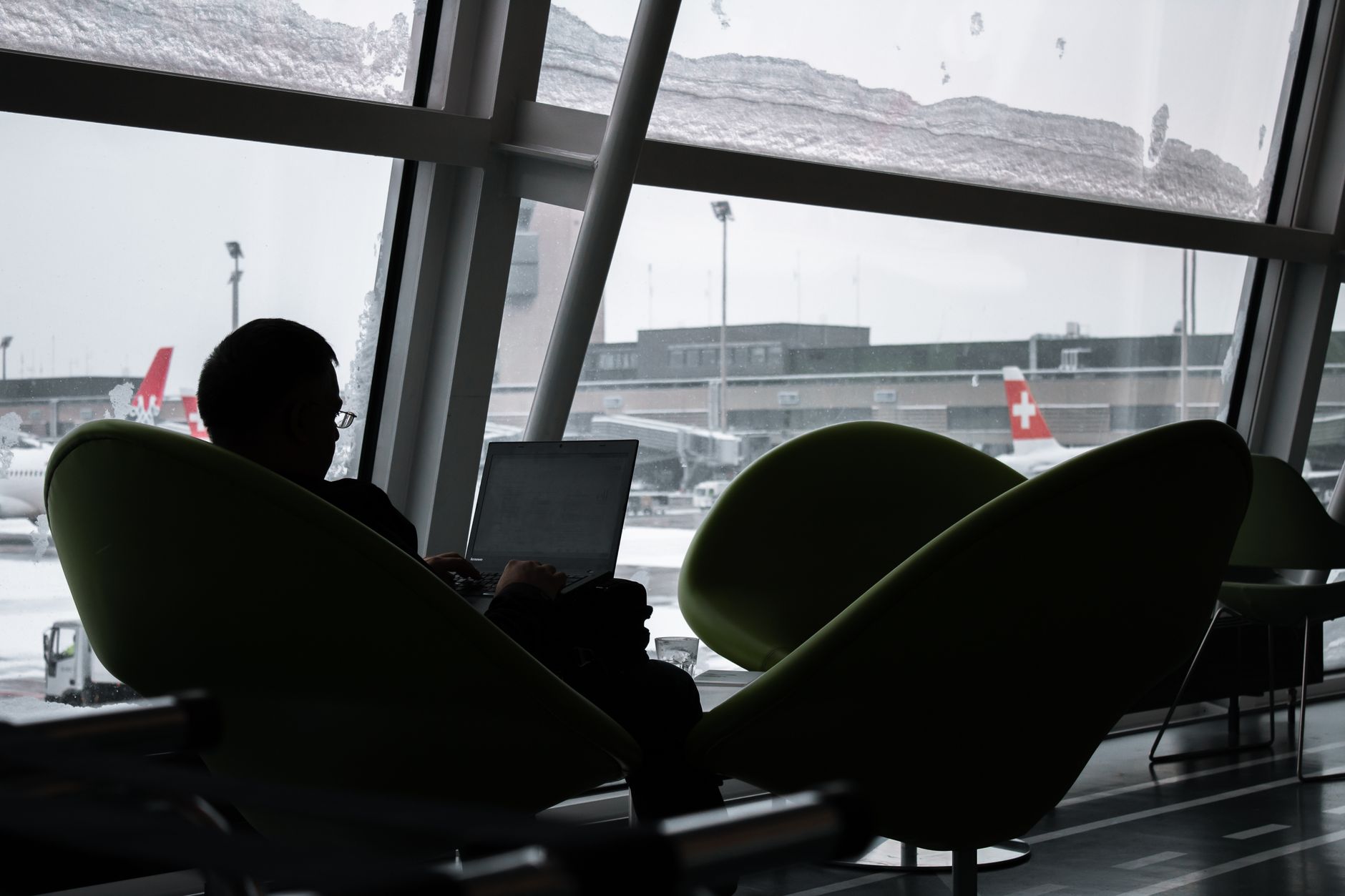 Pessoa usando power bank Anker para carregar MacBook em aeroporto